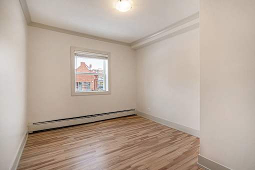 A room with a window and wooden flooring.