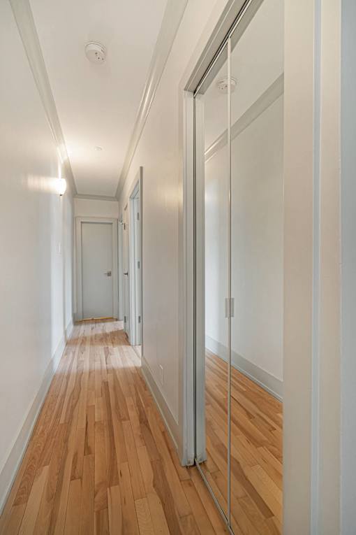 A long hallway with wood floors and white walls.