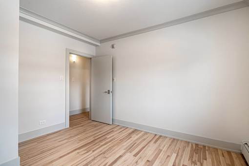 A room with a white door and a wooden floor.