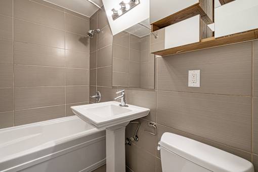 A white sink is on a stand in a bathroom with a white toilet and a bathtub.