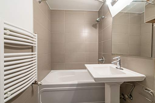 A white bathroom with a white tub and sink.