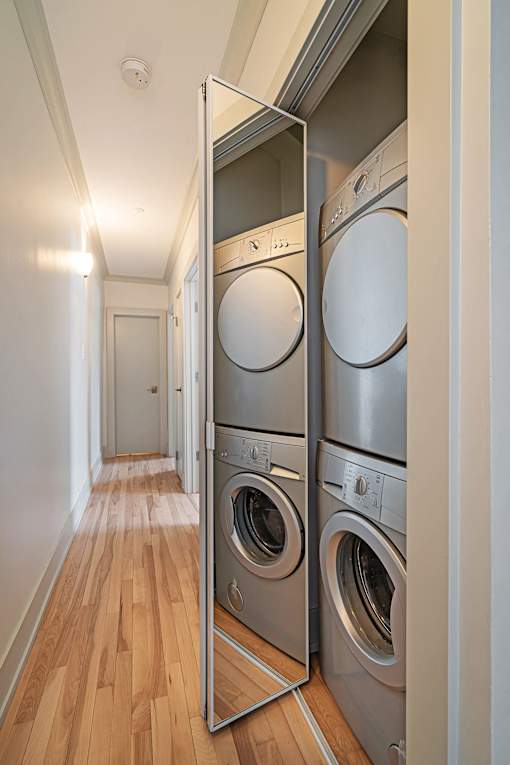 A row of washing machines are stacked in a laundry room.