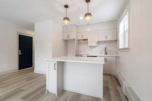 A kitchen with white cabinets and a white island.