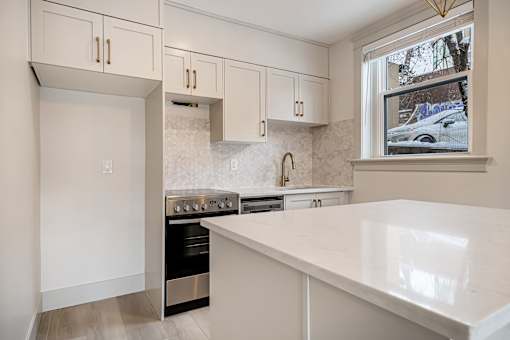 A kitchen with white cabinets and a marble backsplash.