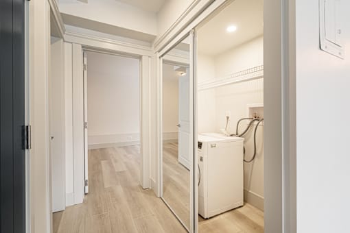 A white door is open to a room with a wood floor.