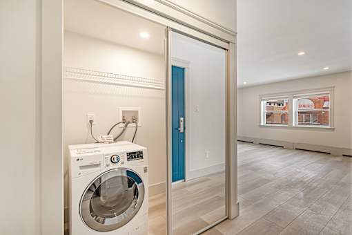 A washing machine is sitting in a room with a blue door.