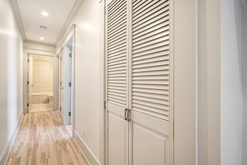 A hallway with a wooden floor and white walls.