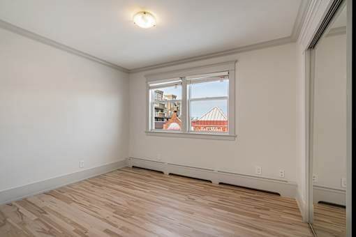 A room with a window showing a view of a building outside.