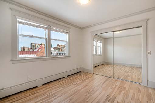 A room with a wooden floor and a large mirror on the wall.