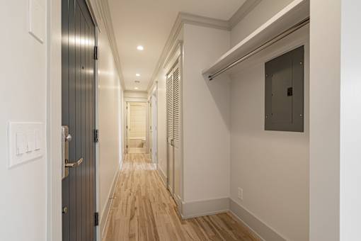 A long hallway with wood floors and white walls.