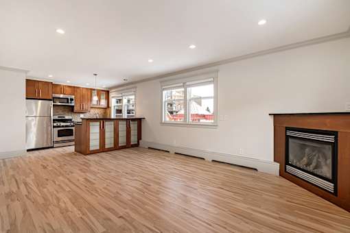 A large, empty room with a fireplace and wooden floors.
