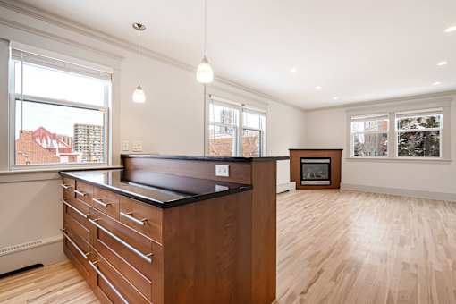 A kitchen with a black counter top and wooden floors.