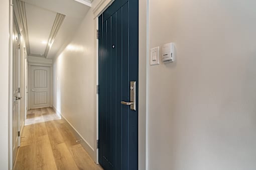 A hallway with a blue door and white walls.