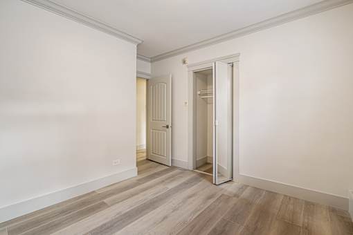 A room with a white door and a wooden floor.