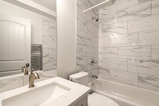 A white bathroom with a marble tile wall.