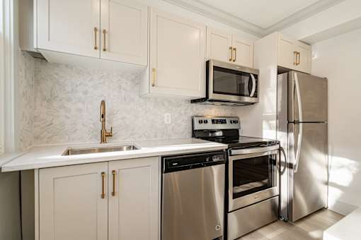 A kitchen with a stove, oven, refrigerator, and sink.