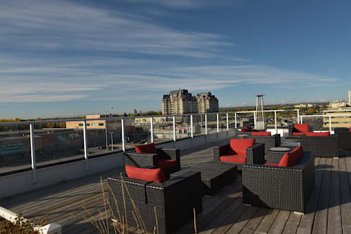 A rooftop patio with black furniture and a view of the city.
