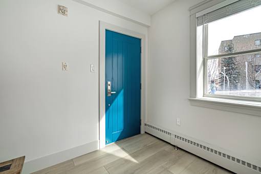 A room with a blue door and a window showing a city view.