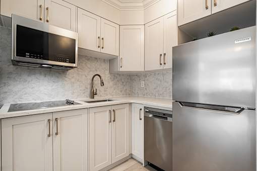 A kitchen with a stainless steel refrigerator and a microwave above the sink.