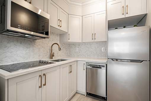 A kitchen with a stainless steel refrigerator and a microwave above the stove.