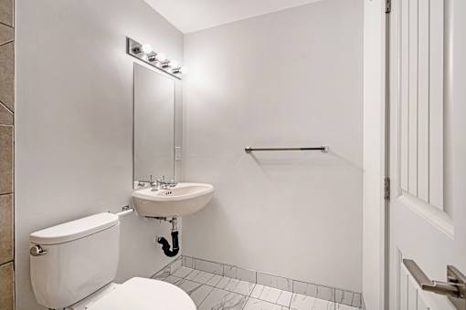 A white bathroom with a toilet, sink, and mirror.
