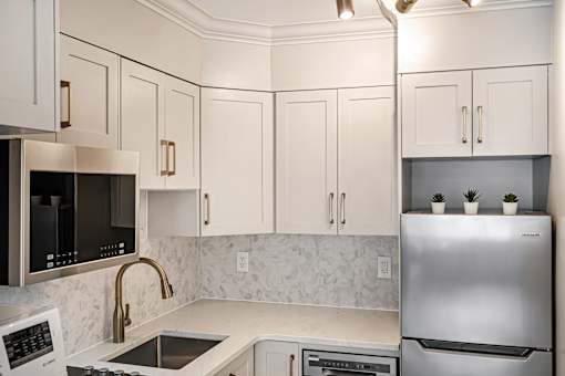 A kitchen with a stainless steel refrigerator, microwave, and oven.