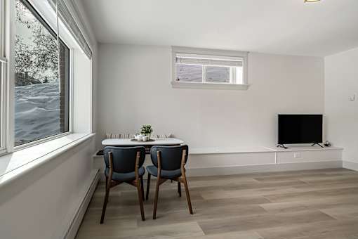 A room with a table and chairs and a television.