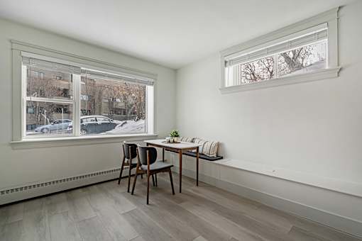 A room with a table and chairs by a window.