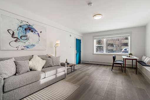 A living room with a grey couch and a painting on the wall.