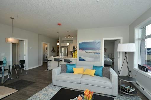 A living room with a grey couch and a painting on the wall.