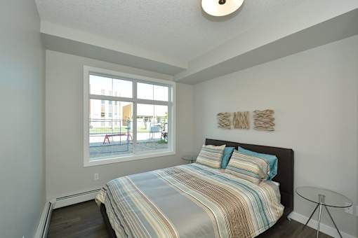 A bedroom with a bed, a window, and a wall hanging.