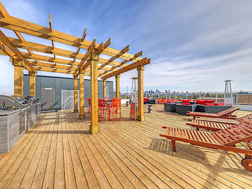 A wooden deck with red chairs and tables.