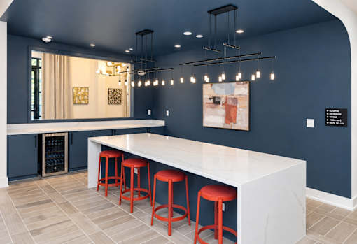 A bar area with a white counter and red stools.