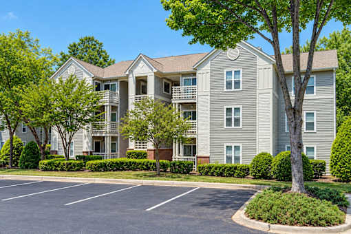 A large apartment building with a parking lot in front.