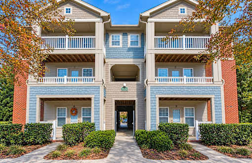 A two-story building with a blue and red exterior and a green lawn in front.