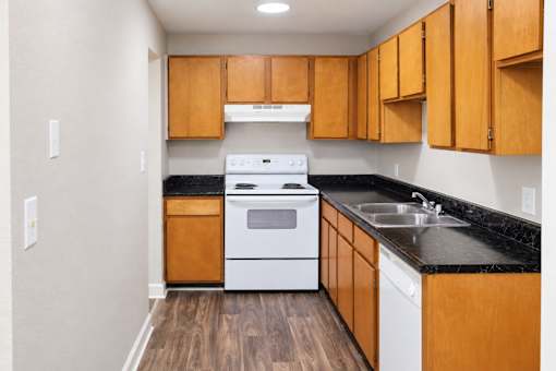 A kitchen with wooden cabinets and a white stove top oven.