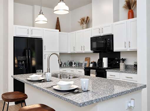 A kitchen with a granite countertop and white cabinets.