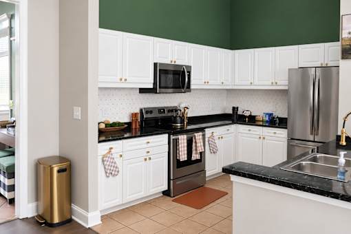 A kitchen with white cabinets and black countertops.