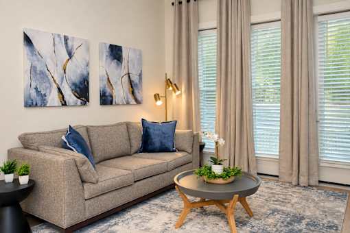 A living room with a beige couch, a coffee table, and two abstract paintings on the wall.