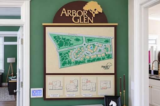 A map of Arbor Glen is displayed on a wall above a framed set of four floor plans.