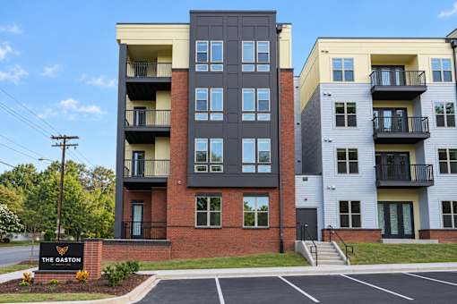 The Gaston apartment complex has a parking lot in front.