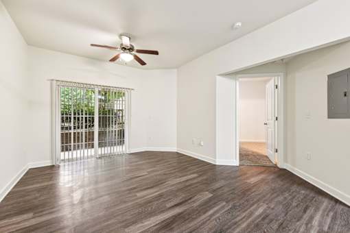 A room with a ceiling fan and sliding glass doors.