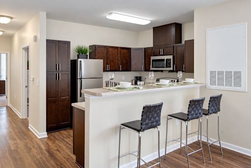 A kitchen with a white counter top and black bar stools.