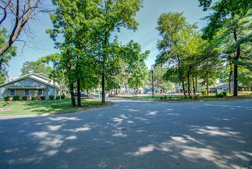 A tree-lined street with a house on the left.