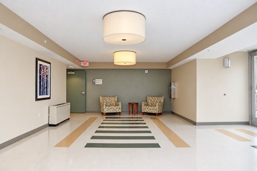 A hallway with a striped rug and two chairs.