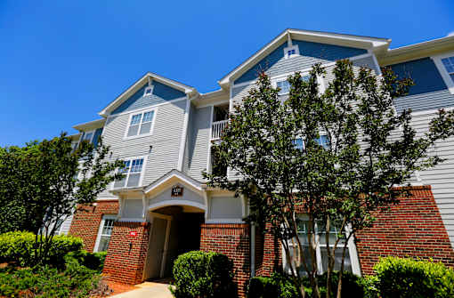 A two-story house with a red brick base and a grey upper section with white trim.