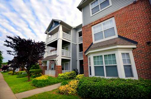 A two-story brick building with a balcony and a small porch.