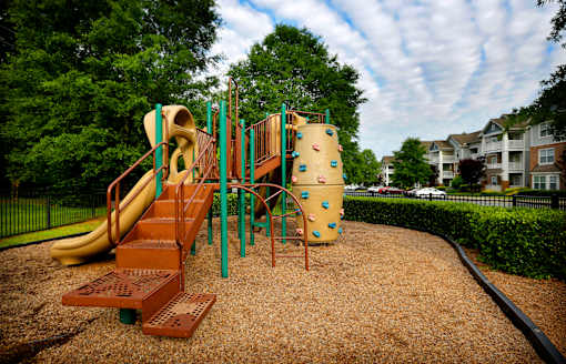 A playground with a slide, climbing wall, and a tunnel.