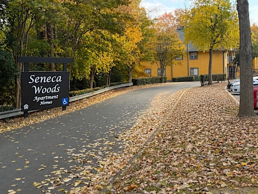 A black sign with white lettering that says Seneca Woods Apartment Homes.