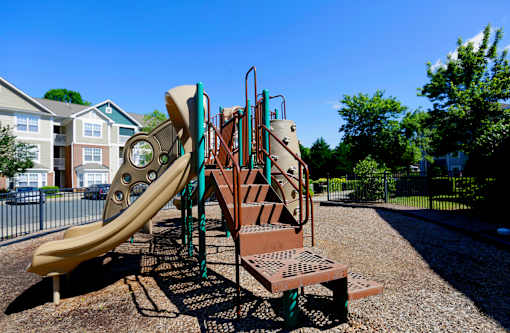 A playground with a yellow slide and a brown climbing structure.